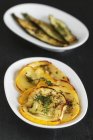 Preserved courgette - antipasti on white plates on black background — Stock Photo