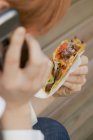Closeup cropped view of woman on the phone holding a taco in hand — Stock Photo