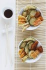 Vegetable tempura with soy sauce over straw mat — Stock Photo
