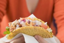 Closeup view of woman holding chicken taco on paper napkin — Stock Photo