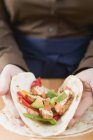 Closeup view of hands folding chicken filled Tortilla — Stock Photo