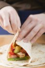 Close-up vista de mãos dobrar frango cheio Tortilla — Fotografia de Stock