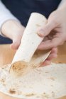 Vista ravvicinata di mani che rotolano una Tortilla — Foto stock