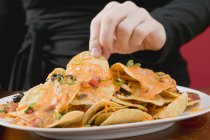 Mão chegando para chips de tortilla — Fotografia de Stock