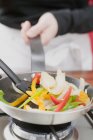 Человек Sauting овощи в сковороде — стоковое фото