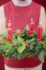 Cropped view of woman holding Advent wreath with four burning candles — Stock Photo