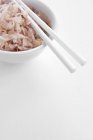 Finely chopped onion and chopsticks in a white bowl over white surface — Stock Photo