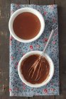 Vista superior de chocolate Blancmange com batedor em duas taças em toalha — Fotografia de Stock