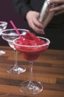 Closeup view of strawberry Daiquiri cocktail in glass and person on background — Stock Photo