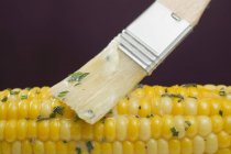 Brosser le maïs avec du beurre d'herbes — Photo de stock
