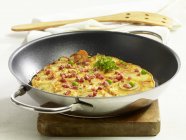 A country omelette in a pan on wooden desk over white surface — Stock Photo