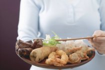 Donna che tiene piatto asiatico — Foto stock