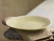 Крупный план пустой тарелки на льняной ткани — стоковое фото
