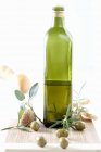 Бутылка оливкового масла с травами и оливками — стоковое фото