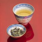 Chá verde em tigela e folhas de chá — Fotografia de Stock