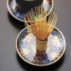 Vista close-up de batedor de chá japonês no disco floral estampado — Fotografia de Stock