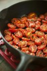 Половинчатые помидоры вишни, приготовленные с солью, перцем и розмарином в сковороде — стоковое фото