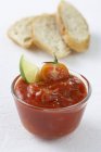 Tomato dip with wedge of lime, slices of white bread  on white surface — Stock Photo