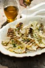 Drizzling Olive Oil Over Grilled Fennel with Fresh Herbs on white plate  over wooden surface — Stock Photo