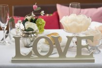 Vista de primer plano de la mesa puesta con decoraciones florales y la palabra Amor - foto de stock