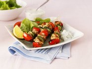 Summery chicken and vegetable kebabs on white plate over towel — Stock Photo