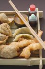 Крупный план азиатских закусок с соусами и палочками на блюдечке — стоковое фото