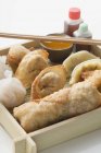 Vista close-up de aperitivos asiáticos em prato com molhos e pauzinhos — Fotografia de Stock