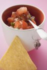 Salsa de tomate em panela com colher, nacho ao lado sobre a superfície rosa — Fotografia de Stock