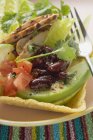 Frango, legumes e folhas de coentro em casca de taco na placa com garfo — Fotografia de Stock