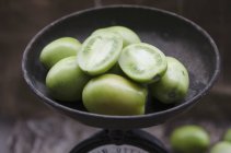 Green tomatoes in antique scales — Stock Photo