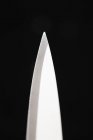 Closeup view of the point of a knife blade on black background — Stock Photo