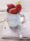 Strawberries in floral-patterned cup — Stock Photo