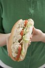 Vista recortada de la mujer sosteniendo sándwich grande con ensalada de pollo - foto de stock