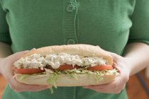 Cropped view of woman holding big sandwich with chicken salad — Stock Photo