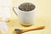 Closeup view of chia seeds in white cup and on spoon — Stock Photo