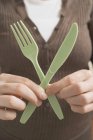 Cropped view of woman holding plastic knife and fork — Stock Photo