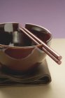 Closeup view of lacquer bowl with chopsticks on brown cloth — Stock Photo