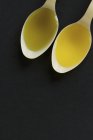 Primo piano vista dall'alto di olio di semi di colza e olio di canapa in cucchiai su sfondo nero — Foto stock