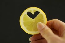 Female hand holding slice of lemon — Stock Photo