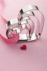 Vista close-up de cortadores de biscoitos em forma de coração em vários tamanhos e coração vermelho — Fotografia de Stock