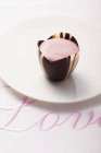 Nahaufnahme von rosa Praline auf Stoff bestickt mit dem Wort Liebe — Stockfoto