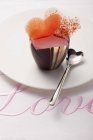 Primo piano vista di rosa pralina decorata con cuori su un panno ricamato con la parola Amore — Foto stock