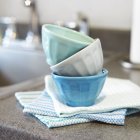 Nahaufnahme von gestapelten Schüsseln und Handtüchern auf einem Küchentisch — Stockfoto