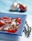 Triglie alla livornese - red mullet with tomatoes, onions and thyme on blue plate — Stock Photo