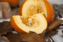 Sliced pumpkin with autumnal leaves — Stock Photo