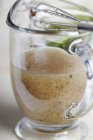 Closeup view of homemade Italian Vinaigrette salad dressing in a glass pitcher with a whisk — Stock Photo