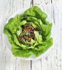 Salat auf einem weißen Teller über einem Holztisch — Stockfoto