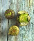 Tre pomodori su legno verde angosciato — Foto stock
