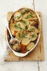 Potato bake with sauerkraut and mushrooms in dish over desk — Stock Photo