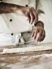 Vista cortada do chef polvilhar massa Gnocchi com farinha — Fotografia de Stock